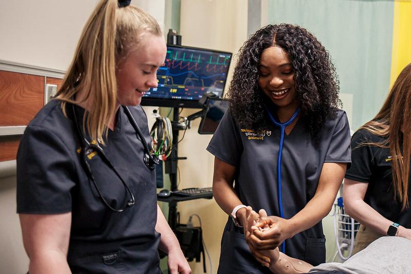 Image shows two MU nursing students working together during a lab